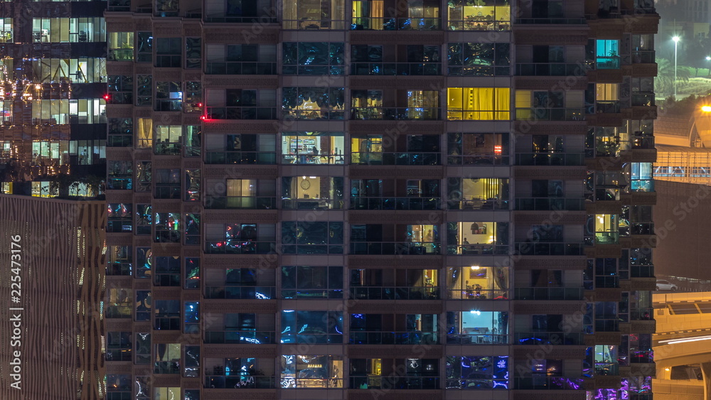 Windows of the multi-storey building of glass and steel lighting inside and moving people within timelapse