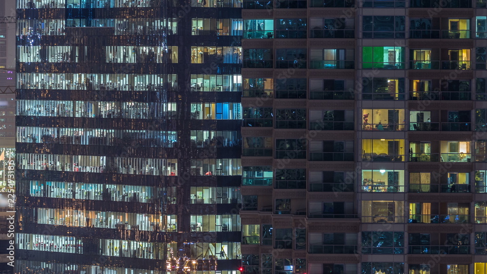 Windows of the multi-storey building of glass and steel lighting inside and moving people within timelapse