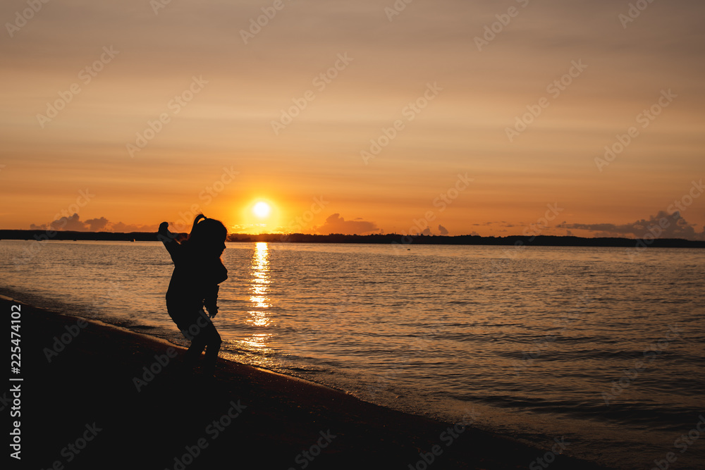 Fototapeta premium silhouette of a child on the background of the setting sun on the beach