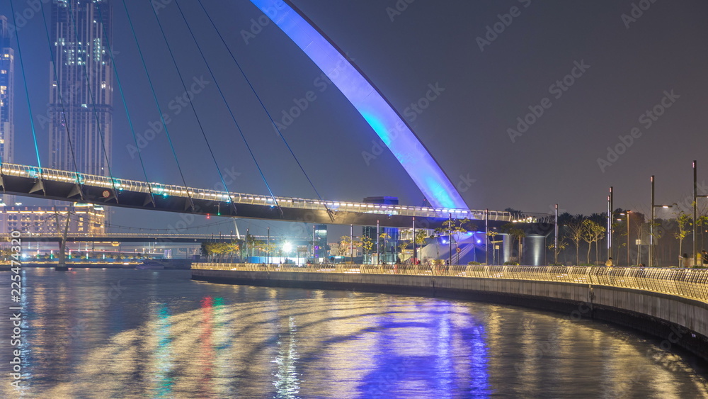 Obraz premium Futuristic Pedestrian Bridge over the Dubai Water Canal Illuminated at Night timelapse, UAE.