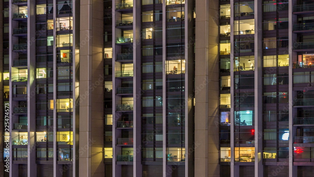 Windows of the multi-storey building of glass and steel lighting inside and moving people within timelapse Windows of the multi-storey building of glass and steel lighting inside and moving people within timelapse