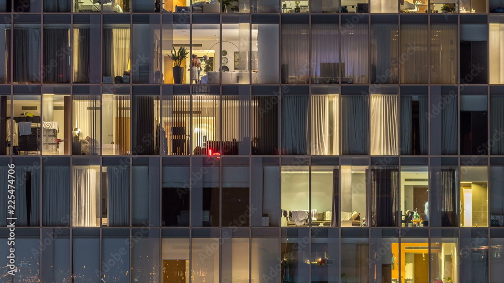 Windows of the multi-storey building of glass and steel lighting inside and moving people within timelapse Windows of the multi-storey building of glass and steel lighting inside and moving people within timelapse