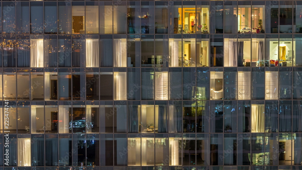 Windows of the multi-storey building of glass and steel lighting inside and moving people within timelapse Windows of the multi-storey building of glass and steel lighting inside and moving people within timelapse