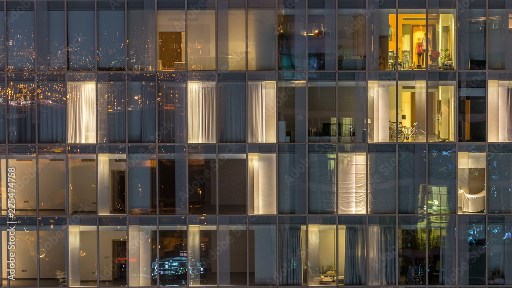 Windows of the multi-storey building of glass and steel lighting inside and moving people within timelapse Windows of the multi-storey building of glass and steel lighting inside and moving people within timelapse