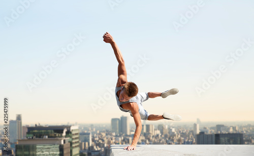 extreme sport, parkour and people concept - young man jumping high over tokyo city background