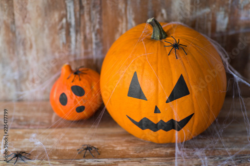 halloween and holidays concept - pumpkin and squash with scary faces, spiders and cobweb