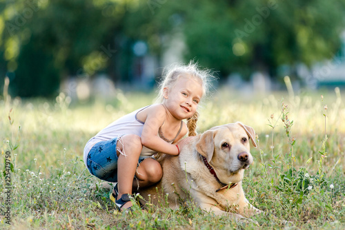 Little girl is playing with a labrador in the park.