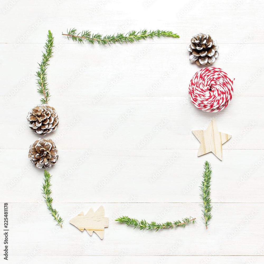 Christmas composition. Frame of fir branches, cones, wooden toys, twine for gift on white wooden table Flat lay top view copy space square. Christmas winter decoration, Nature New Year concept