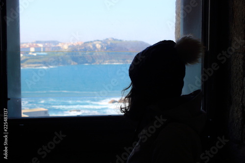 Silhouette of a girl looking out the window.
