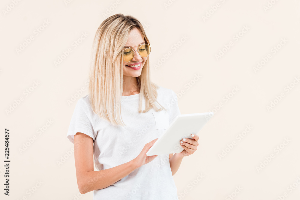 happy stylish woman in eyeglasses using digital tablet isolated on beige happy stylish woman in eyeglasses using digital tablet isolated on beige