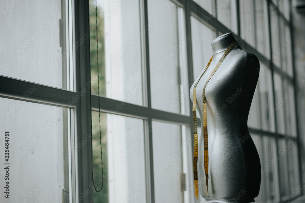 Tailor dummy with measuring tapes in fashion studio. Grey dummy with