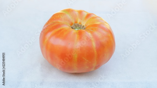 tomate reliquia o de herencia (heirloom en inglés) de color naranja y amarillo en fondo blanco recién cultivado y recogido del huerto