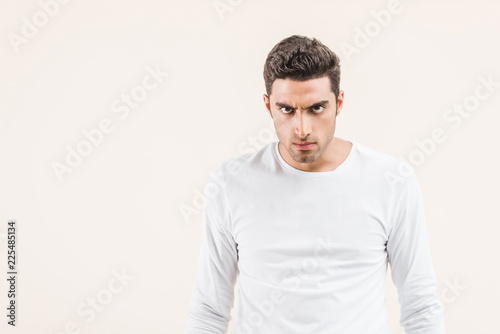 aggressive young man looking at camera isolated on beige