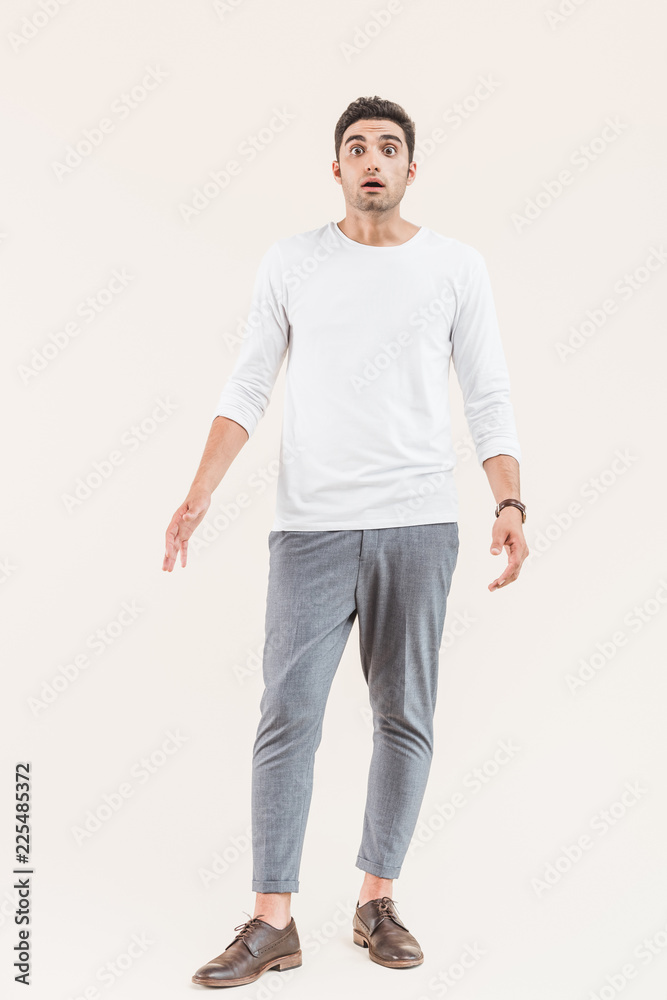 full length view of shocked young man looking at camera isolated on beige full length view of shocked young man looking at camera isolated on beige