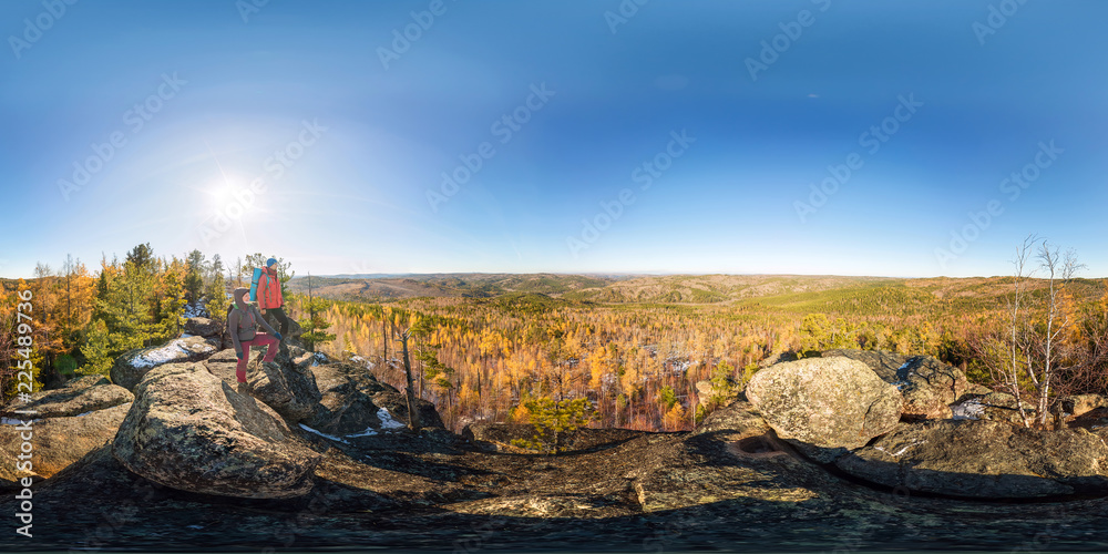 Couple of tourists with backpacks man and woman standing on a rock in autumn forest. Spherical 360vr panorama