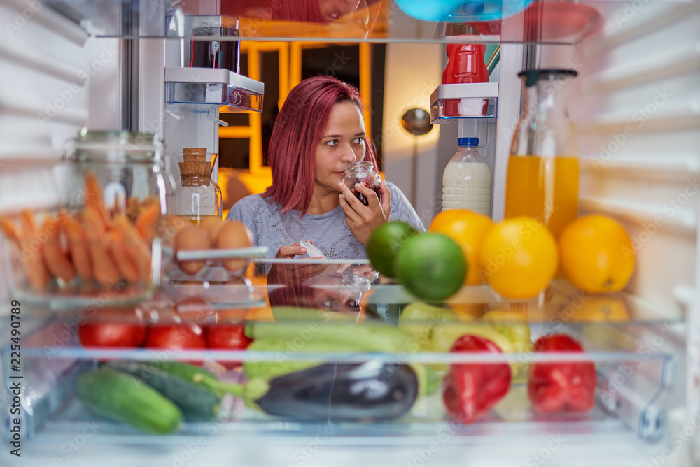Woman looking something to eat late at night. Picture taken from the inside of fridge. Woman looking something to eat late at night. Picture taken from the inside of fridge.