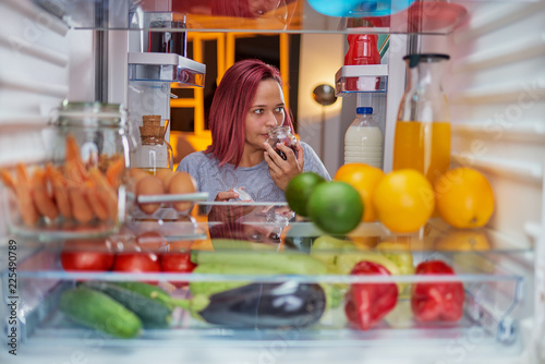 Woman looking something to eat late at night. Picture taken from the inside of fridge.