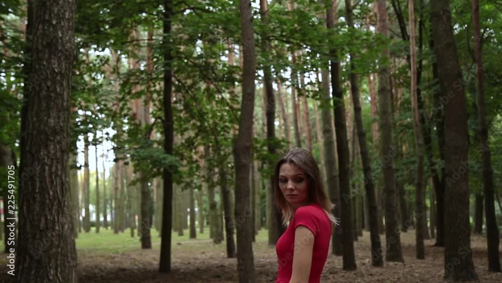 A very beautiful and fashionable woman in a red dress walks through the forest. A very beautiful and fashionable woman in a red dress walks through the forest.