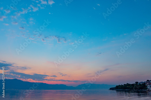 Beautiful sunrise at the beach, amazing colors, light beam shining through the cloudscape over the mountain in the background. Seascape in Croatia, island Brac.