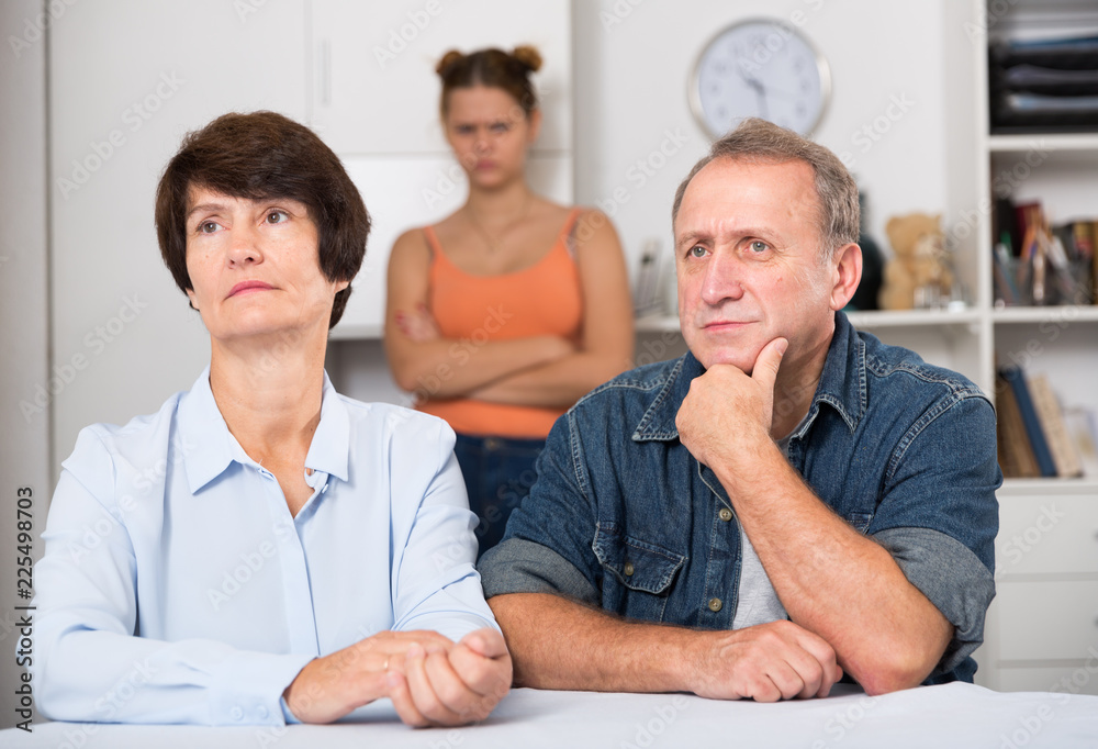 Fototapeta premium Adult daughter is sympathying her sad parens who are sitting at the table