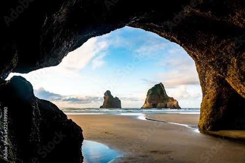 View from the cave of the beautiful Wharariki Beach with famous rocks. Sunset scene golden light and silhouette. Nelson, South Island, New Zealand.