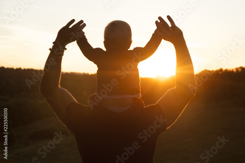 Father and son watching the sunset outdoors in the autumn evening