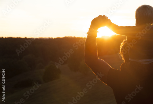 Father and son watching the sunset outdoors in the autumn evening