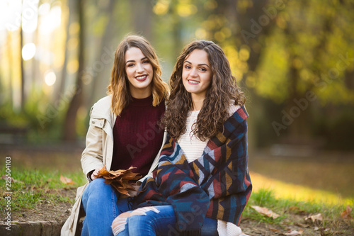 Two beautiful young women drinking coffee outside in the autmn