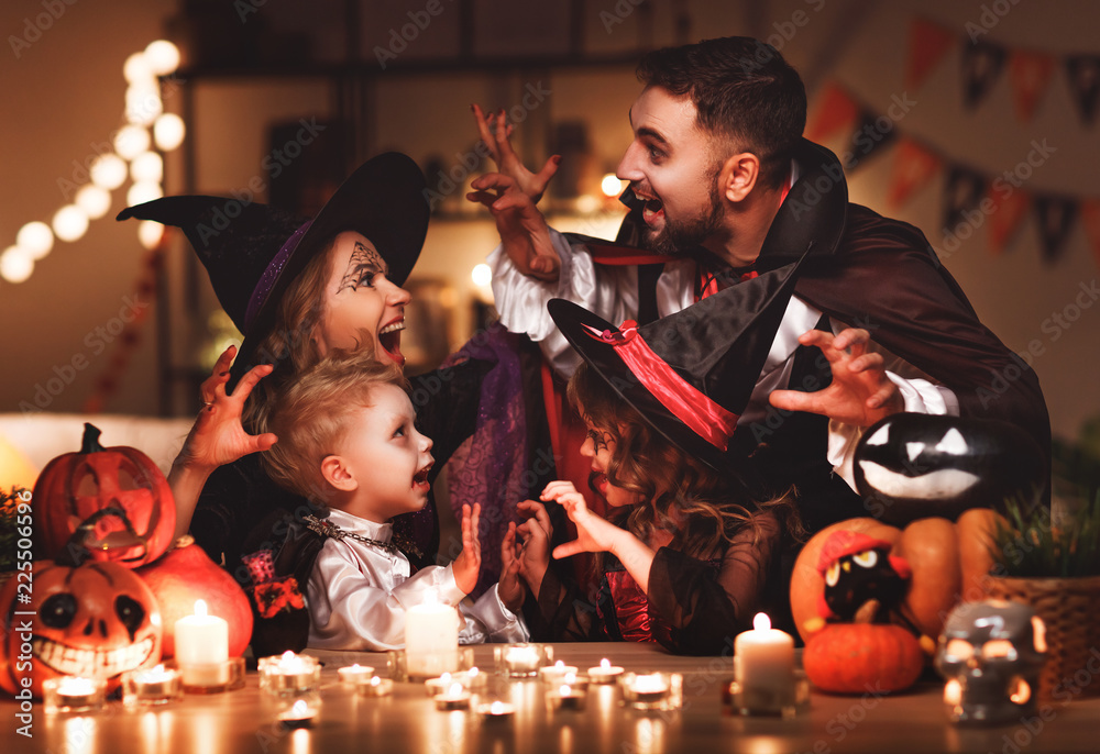 Obraz premium happy family mother father and children in costumes and makeup on Halloween in dark home