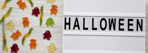 Fototapeta Naklejka Na Ścianę i Meble -  'Halloween' word on modern board, jelly monsters and worms on white wooden background, overhead view. From above, top view, flat lay.