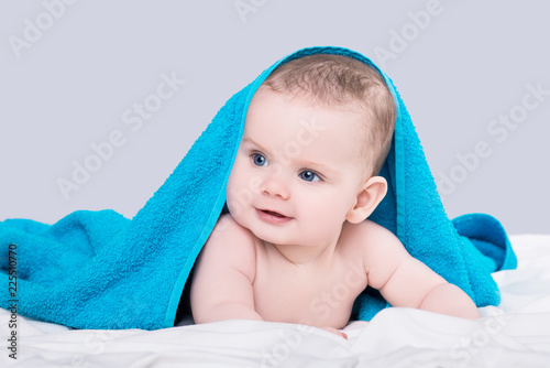 Baby girl or boy after shower with towel on head over grey background, isolated