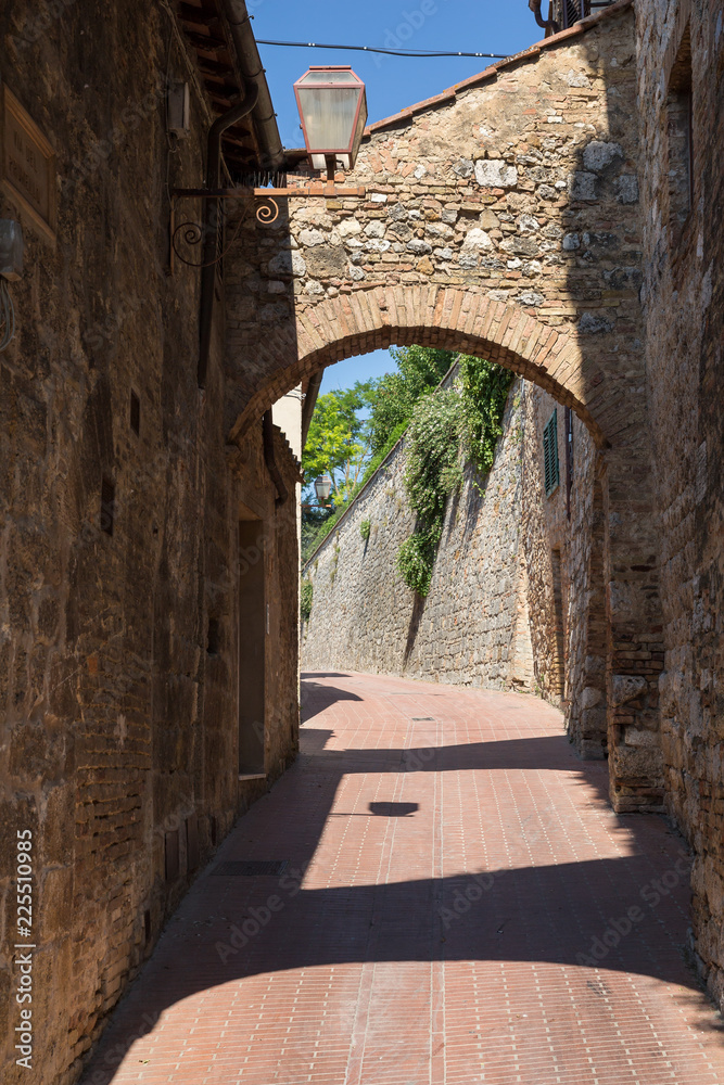 Obraz premium Brick archway and narrow street in San Gimignano, Italy
