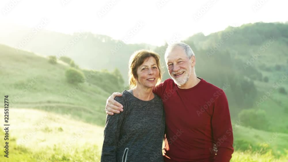 Senior couple runners standing on meadow outdoors at sunrise in nature. Senior couple runners standing on meadow outdoors at sunrise in nature.