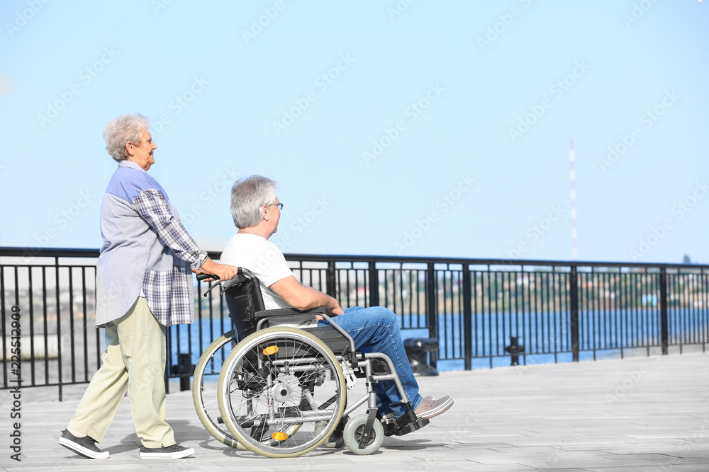 Senior man in wheelchair and his wife outdoors Senior man in wheelchair and his wife outdoors