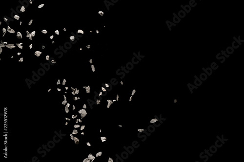 Quadro su tela Split debris of stone exploding against black background.