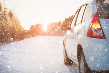 White car on a winter road through a snow covered forest. 