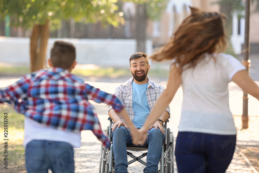 Young man in wheelchair playing with his family outdoors Young man in wheelchair playing with his family outdoors
