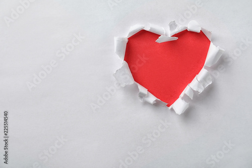 Hole in shape of heart on white paper