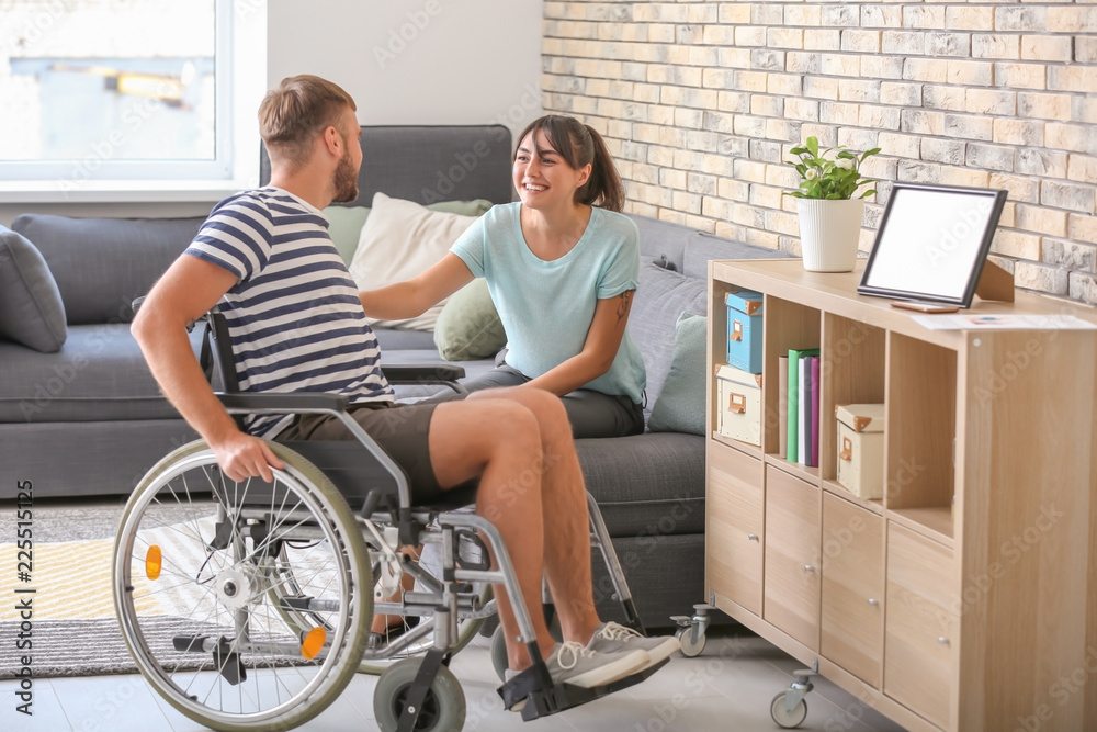 Young man in wheelchair and his wife at home Young man in wheelchair and his wife at home