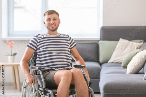 Happy young man in wheelchair at home