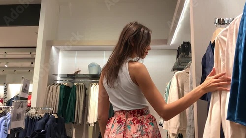 young beautiful emotional modern woman walks through the shopping center, looks at fashion things in clothing stores