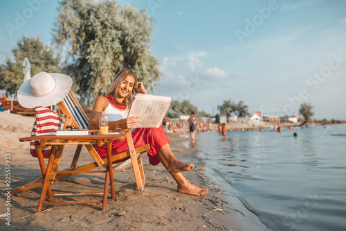 Beautiful woman reading newspaper on the beach
