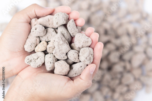 Foto Closeup hand holding pumice stone or volcanic rocks on white background for cact