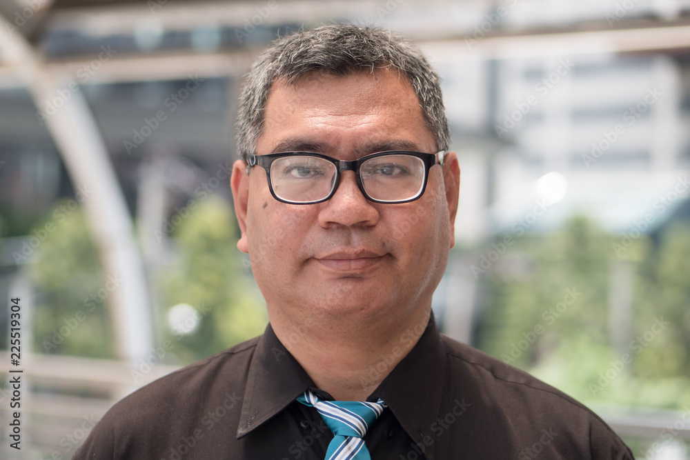 Fototapeta premium old south east asian business man face; face portrait of old senior southeast asian businessman, formal office worker with eye glasses and grey hair; south east asian middle age to senior man model
