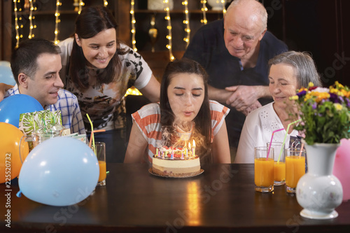 Happy family celebrating teenager girl anniversary with birthday cake