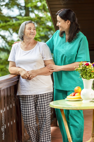 Female nurse consoling elderly woman at home