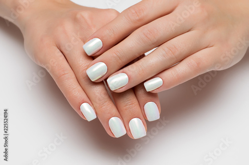 Wedding white pearl manicure on short square nails on a white background close-up.