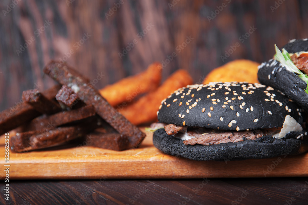Black burger and fast food on wooden background