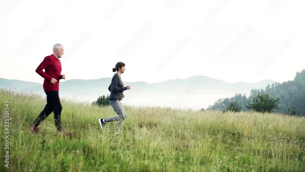 Senior sporty couple running on meadow outdoors in sunny nature. Senior sporty couple running on meadow outdoors in sunny nature.