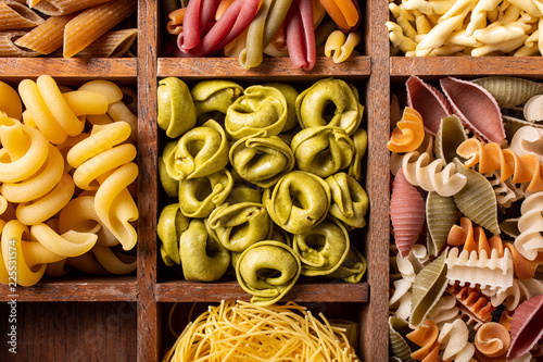 Assorted colorful italian pasta in wooden box. Healthy food background concept. Flat lay, top view.